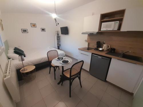 une petite pièce avec un lit, une table et des chaises dans l'établissement Studio Cosy 15 m2 au fond du jardin, à Châlons-en-Champagne