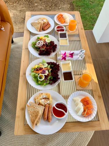 een houten tafel met borden met eten erop bij ชีววิถีเฮิร์บ เวลเนส สเตย์ in Ban Chae Phang (1)