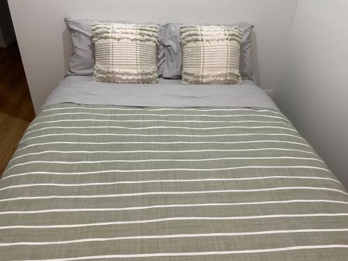 a bed with a gray and white striped sheets and pillows at Chay's Guest House in Coffs Harbour