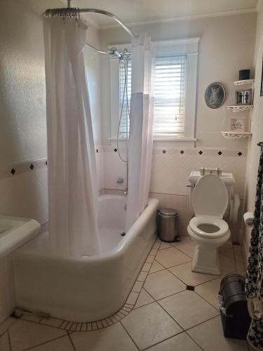 a white bathroom with a tub and a toilet at Wine Country Oasis Private Pool & Spa in Acampo