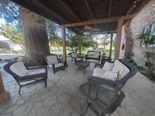 a patio with chairs and tables and a tree at Wine Country Oasis Private Pool & Spa in Acampo