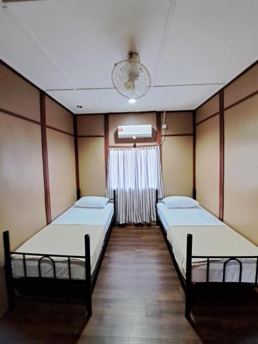 two beds in a room with a window at Benteng Taman Negara in Jerantut
