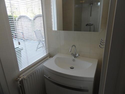 La salle de bains est pourvue d'un lavabo blanc et d'une fenêtre. dans l'établissement Appartement Schuitvlot, à Domburg