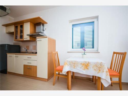 a kitchen with a table and two chairs and a window at Apartments Ruzmarin in Lun