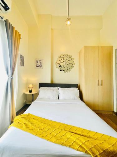 Un dormitorio con una gran cama blanca con una manta amarilla. en 29 Chic Studio Escape, en Iloilo City
