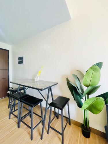 Una mesa y sillas en una habitación con una planta. en 29 Chic Studio Escape, en Iloilo City