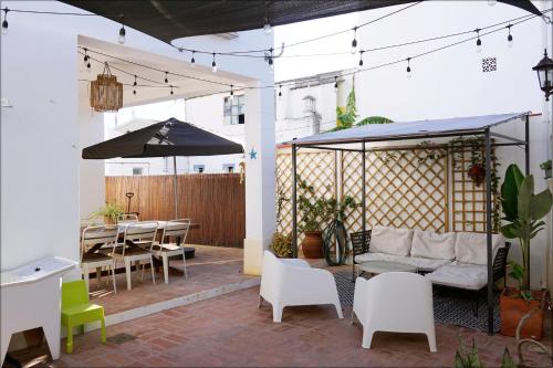 a patio with a couch and chairs and an umbrella at Casa da Praia - Manta Rota in Manta Rota