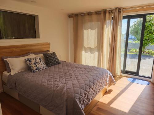 a bedroom with a bed and a large window at Sunny Nook in Auckland