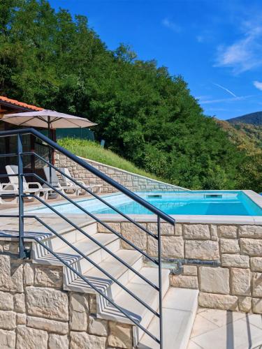 a swimming pool with stairs next to a stone wall at Challet Bella in Poljanica Bistranska