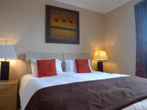 a bedroom with a large bed with two red pillows at Ashburnham Hotel in Pembrey