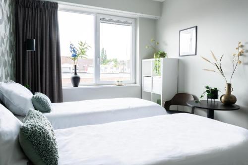 two beds in a bedroom with a window at Trendy Room w Free Parking & Private Bathroom in Raamsdonksveer