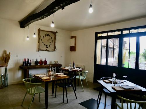 un restaurant avec des tables et des chaises et une horloge sur le mur dans l'établissement Chambres d'Hôtes et Gîte de La Vieille Ecluse, à Quend