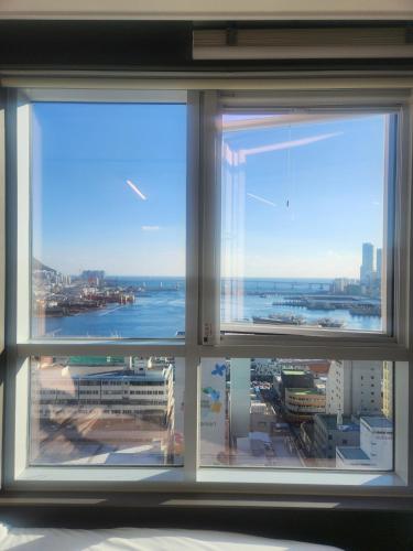 a window with a view of a city and the ocean at Brand New Residence with Family in Busan