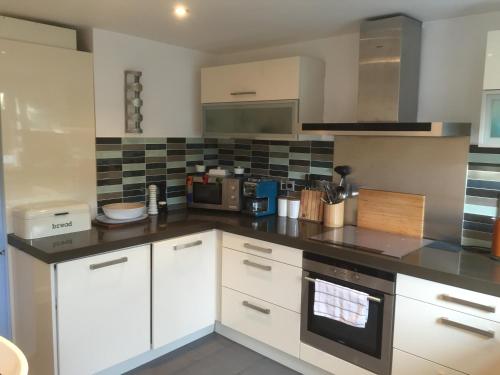a kitchen with white cabinets and a black counter top at Rugby Lodge in Dublin