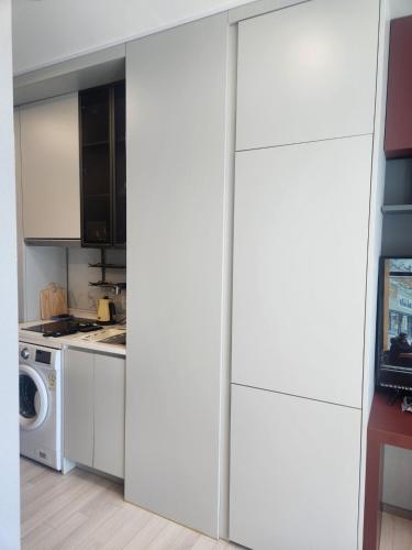 a kitchen with white cabinets and a washer and dryer at Brand New Residence with Family in Busan