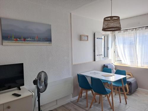 un salon avec une table, des chaises et une télévision dans l'établissement Studio du Fortin, au Cap d'Agde