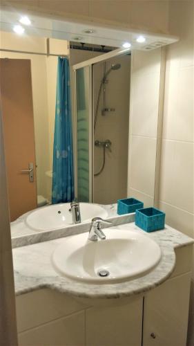 une salle de bain avec un lavabo et un grand miroir dans l'établissement Studio du Fortin, au Cap d'Agde