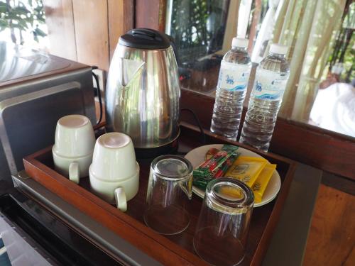 a tray with a coffee pot and cups and water bottles at บ้านพระจันทร์เวียน - House of moon phase in Chachoengsao
