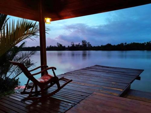 a chair sitting on a dock next to a lake at บ้านพระจันทร์เวียน - House of moon phase in Chachoengsao