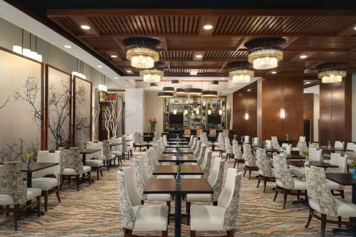 a dining room with tables and white chairs at Embassy Suites Chattanooga Hamilton Place in Chattanooga