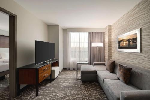 a hotel room with a couch and a flat screen tv at Embassy Suites Chattanooga Hamilton Place in Chattanooga