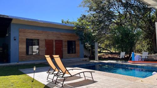 a pair of chairs sitting next to a swimming pool at Apartamento los Guanacastes cerca de Tamarindo con piscina in Santa Cruz
