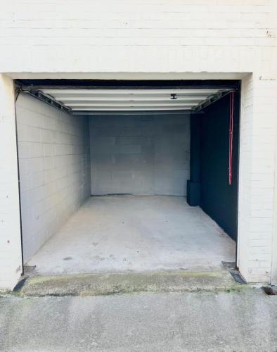 un grand garage avec un mur blanc et une porte bleue dans l'établissement RDC familial à 2 min à pieds de la plage de Berck avec Garage privé, à Berck-sur-Mer