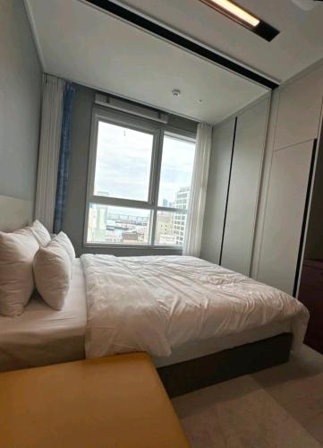 a bedroom with a large bed with a large window at Brand New Residence with Family in Busan