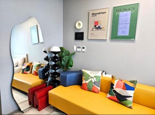 a room with two yellow couches and a mirror at Brand New Residence with Family in Busan