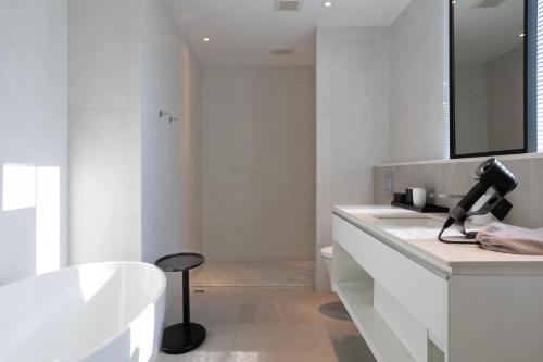 a white bathroom with a tub and a sink at Manho Hotel in Taichung