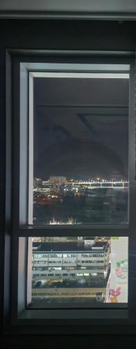 a window with a view of a city at night at Brand New Residence with Family in Busan