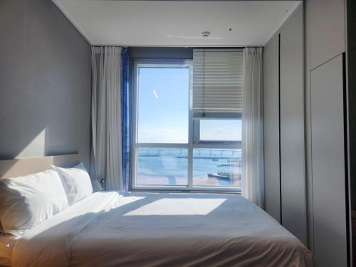 a bedroom with a bed and a large window at Brand New Residence with Family in Busan