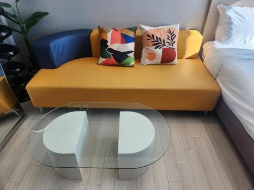 a yellow couch with pillows and a glass table at Brand New Residence with Family in Busan