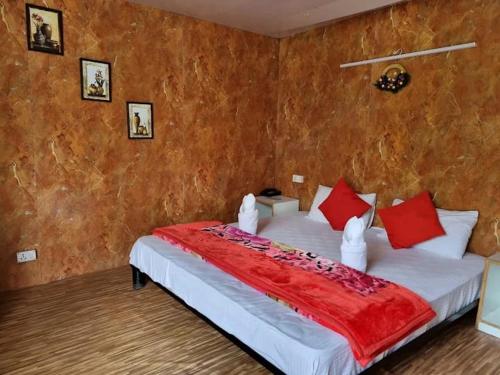 a bedroom with a large bed with red pillows at Soma Caves in Kulu