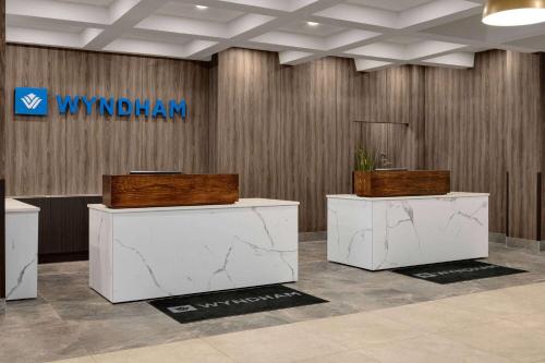 a lobby with two white tables and a sign on a wall at Wyndham Edmonton Hotel and Conference Centre in Edmonton