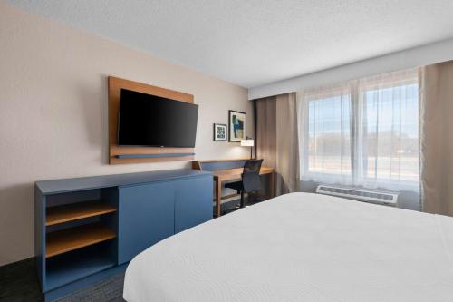 a hotel room with a bed and a desk with a television at Country Inn & Suites by Radisson, Near The National Sports Center, Coon Rapids, MN in Coon Rapids