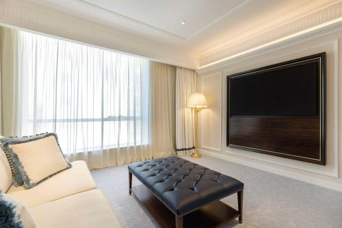 a living room with a couch and a flat screen tv at The Plaza Doha, LXR Hotels & Resorts in Doha
