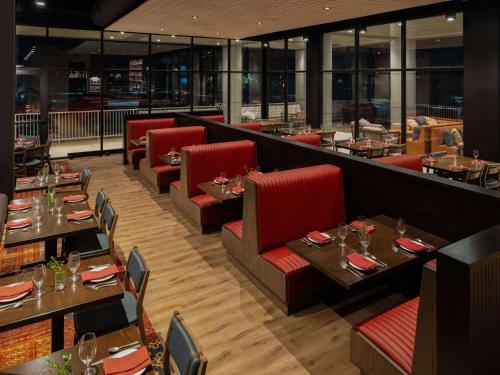 a restaurant with wooden tables and red chairs at Origin Kansas City Riverfront, a Wyndham Hotel in Kansas City