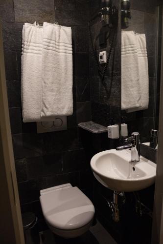 a bathroom with a toilet and a sink and towels at Hellstens Glashus in Stockholm