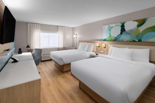 a hotel room with two beds and a television at Wyndham Garden Louisville KY in Louisville