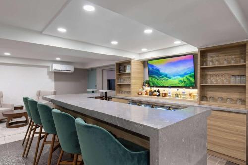 a bar in a room with chairs and a large screen at Wyndham Garden Louisville KY in Louisville
