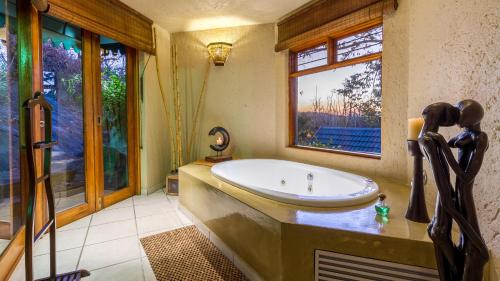 ein Bad mit einer großen Badewanne und einem Fenster in der Unterkunft Jörn's Gästehaus in Nelspruit