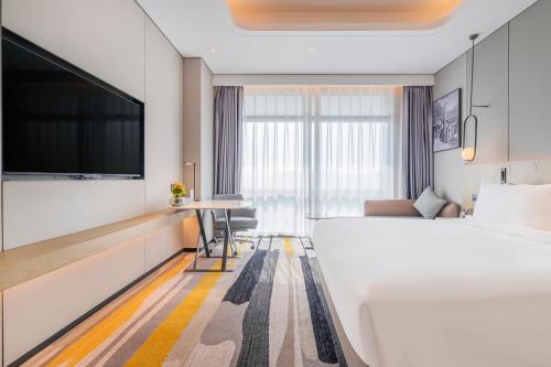 a hotel room with a bed and a flat screen tv at Radisson Hotel, Beijing DaXing Airport in Beijing
