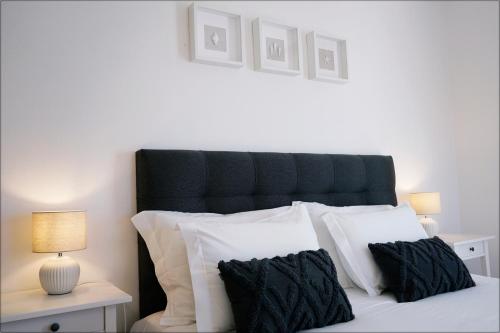 a bed with a black headboard and white pillows at Casa da Praia - Manta Rota in Manta Rota