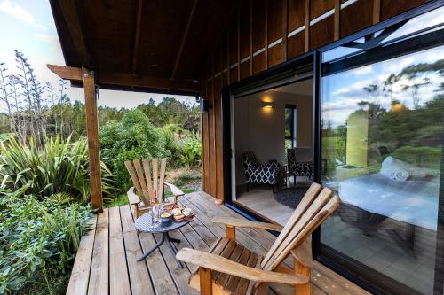 a patio with two chairs and a table on a deck at The Hideout in Mangawhai