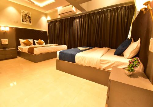 a hotel room with two beds and a table at Dhanvantari Luxury Hotel Near Kokilaben Dhirubhai Ambani Hospital Mumbai in Mumbai