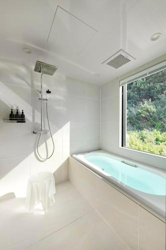 a white bathroom with a tub and a window at The TRAVELERS Chateau Tateyama in Haraoka