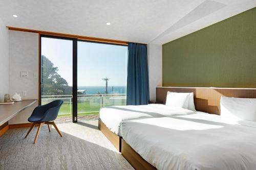 a hotel room with two beds and a large window at The TRAVELERS Chateau Tateyama in Haraoka