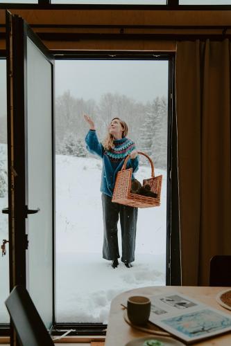 a woman standing in the snow through a glass door at Błogostan in Jodłów