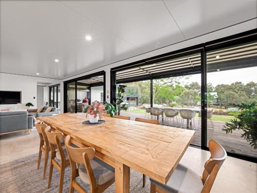 ヤリンガップにあるSeaview - spa and ocean views in luxuryの木製のテーブルと椅子のあるダイニングルーム